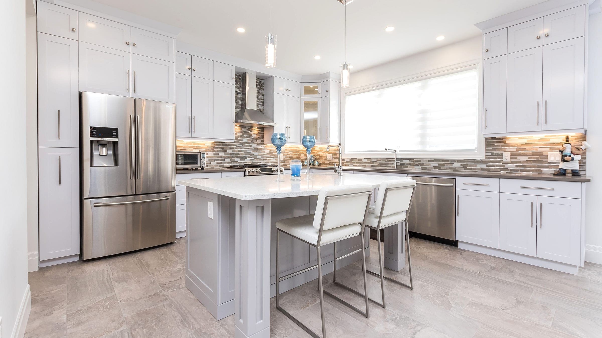A bright custom white kitchen with a quartz island in a completed Black Cedar Homes home in London, Ontario