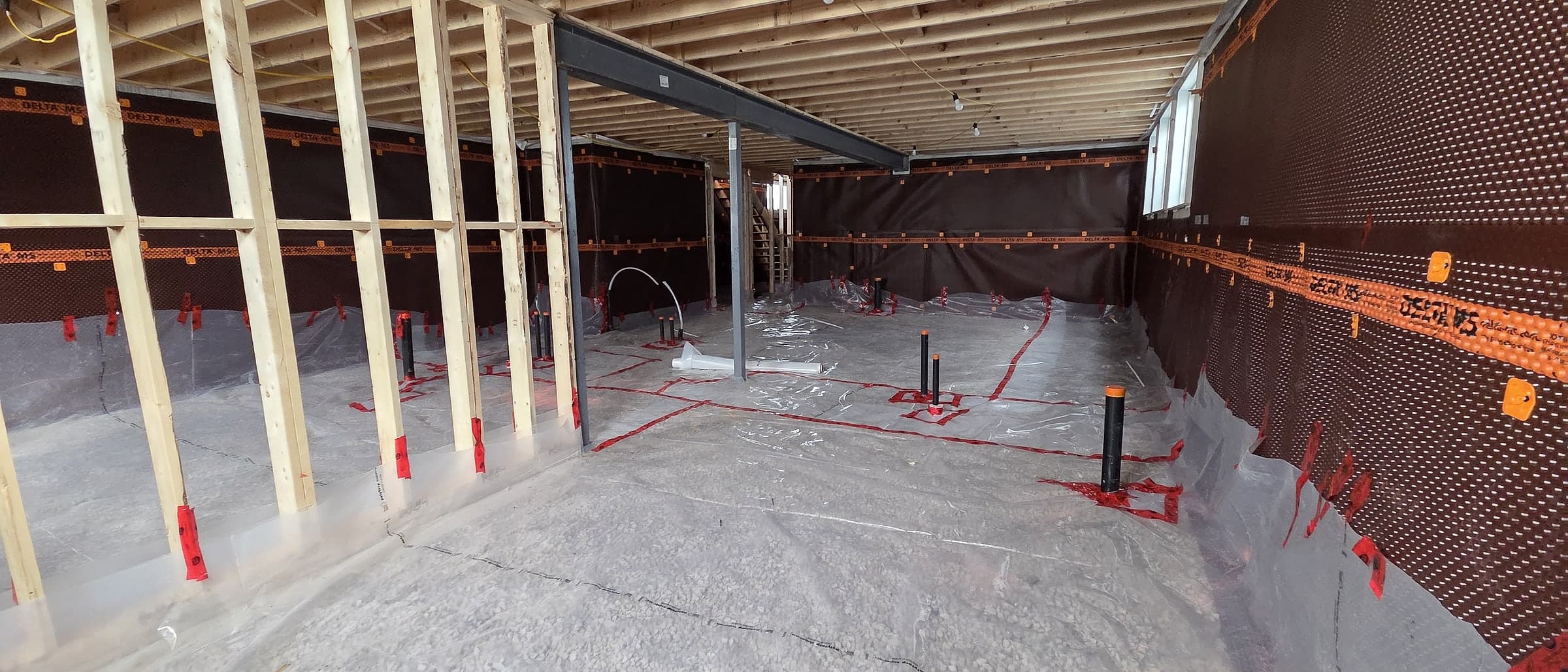 Interior membrane protection along the basement foundation walls of a Black Cedar home during framing