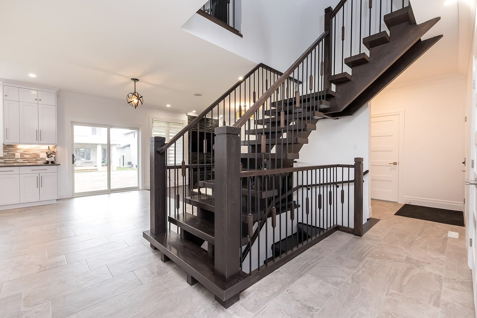 Stained-oak open-riser staircase with iron spindles at Foxwood Crossings