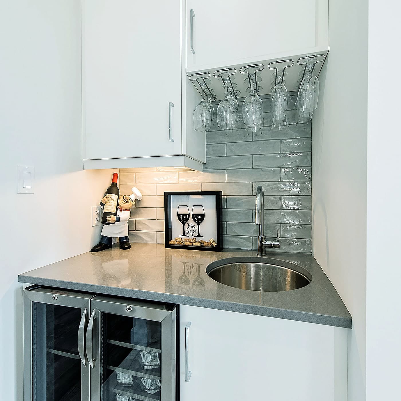 Beverage bar with a stone counter, bar sink, and under-counter fridge