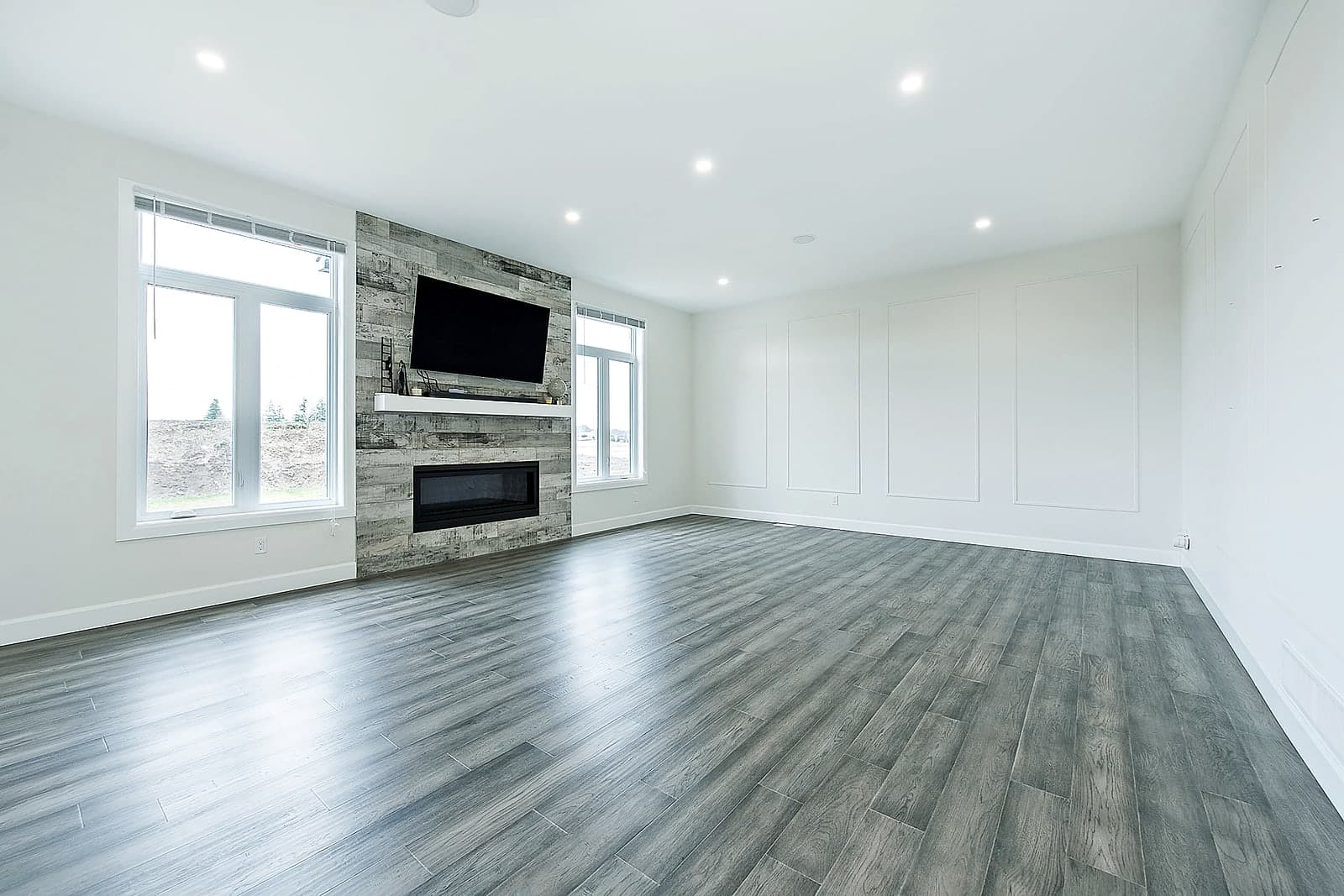 Great room with a wall-mounted television and a wall of windows