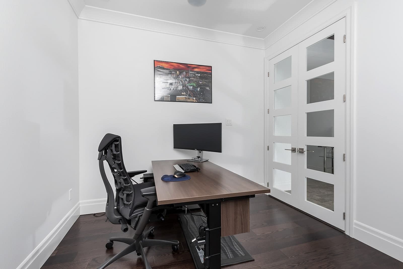 Main-floor home office with a built-in desk and glass French doors