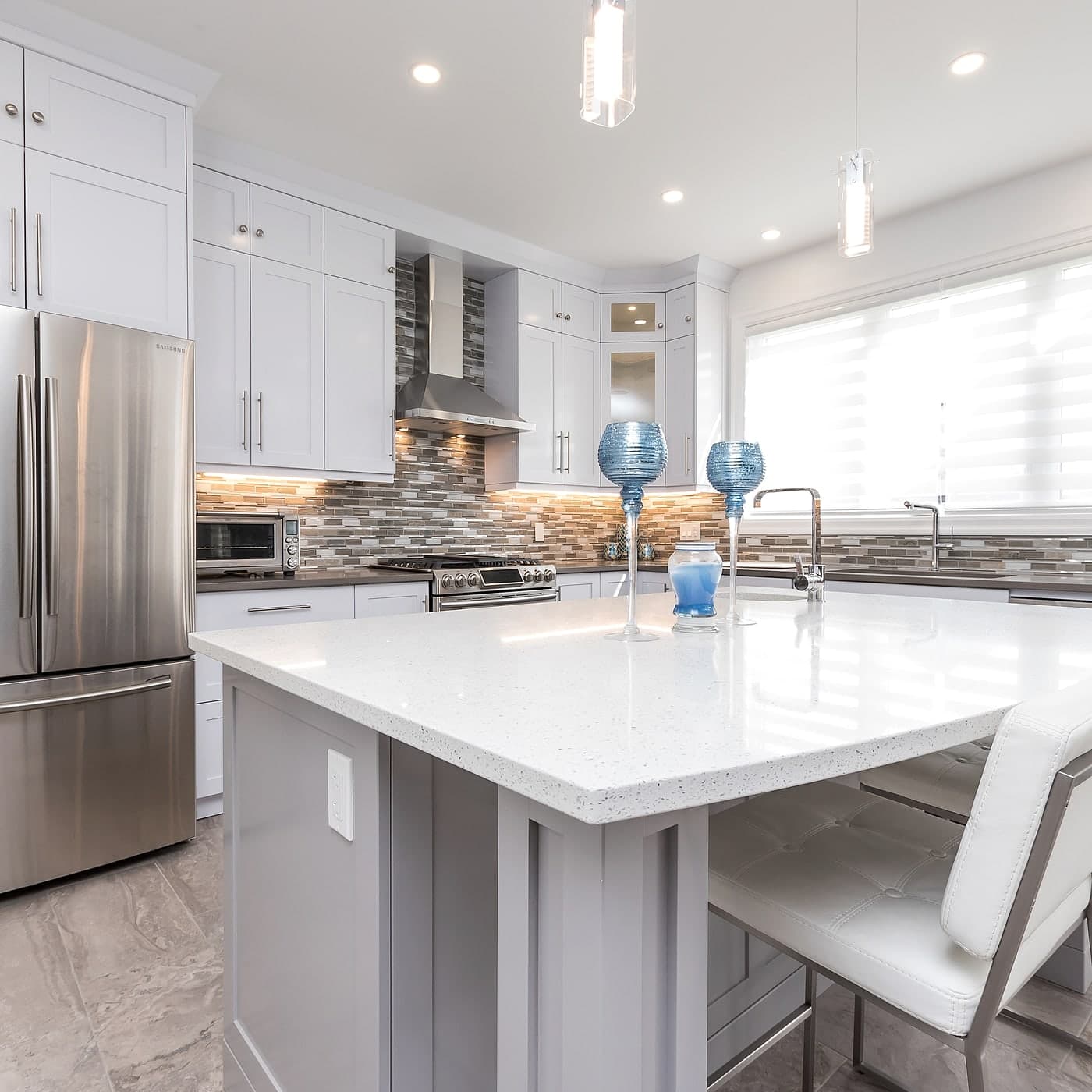 White kitchen with a quartz island and stainless appliances
