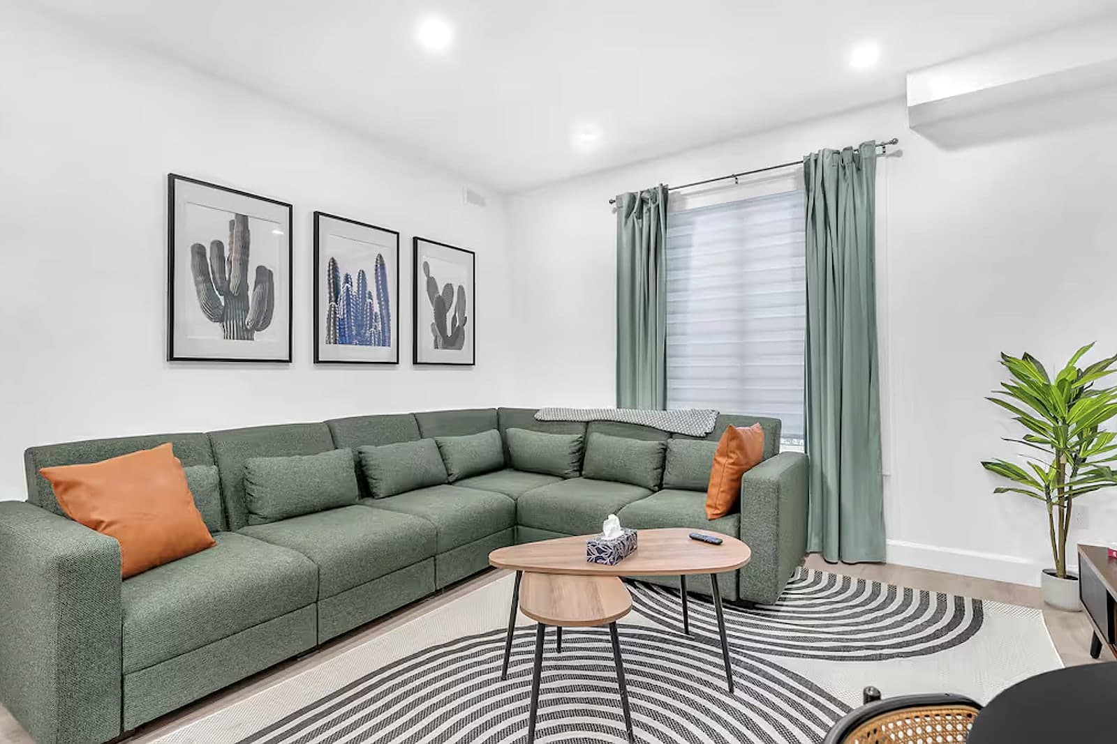 Living room with a green sectional and open sightlines to the kitchen