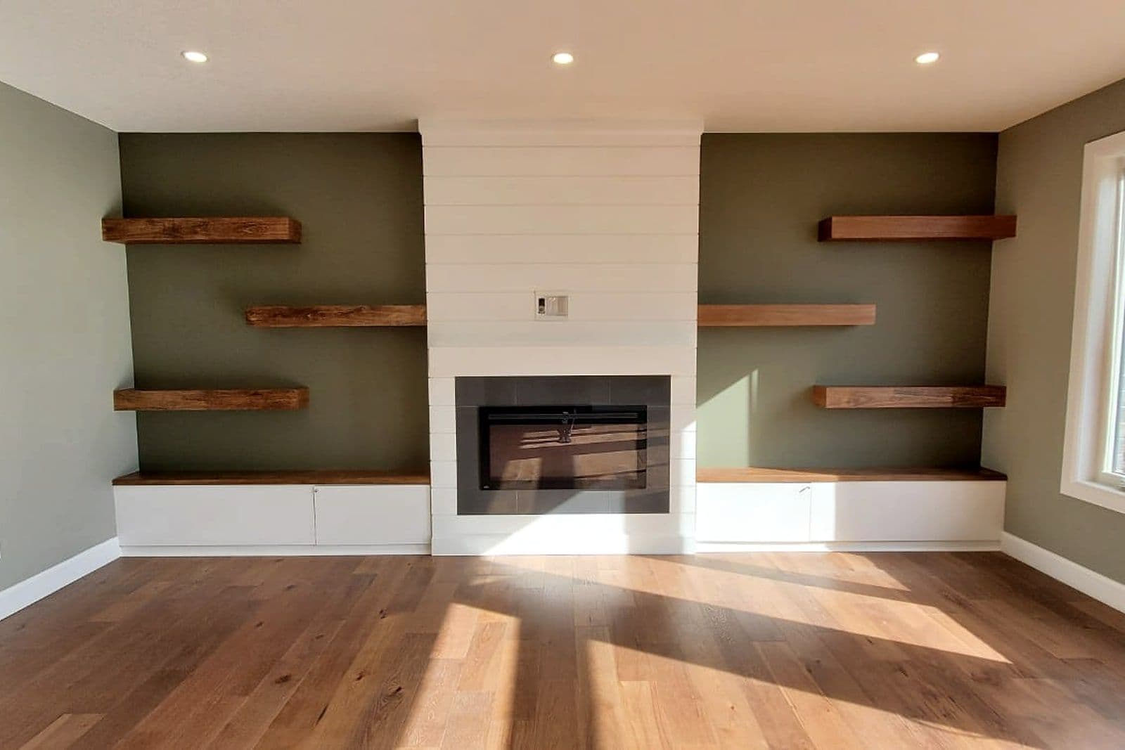 Living room with a linear fireplace and floating shelves