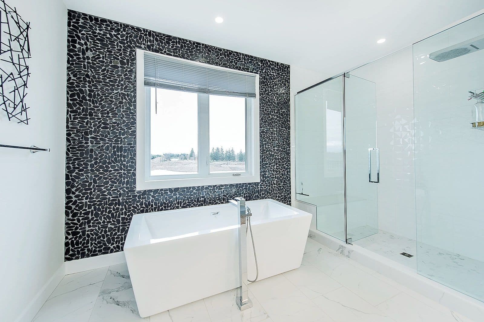 Freestanding soaker tub beside a mosaic-tiled feature wall