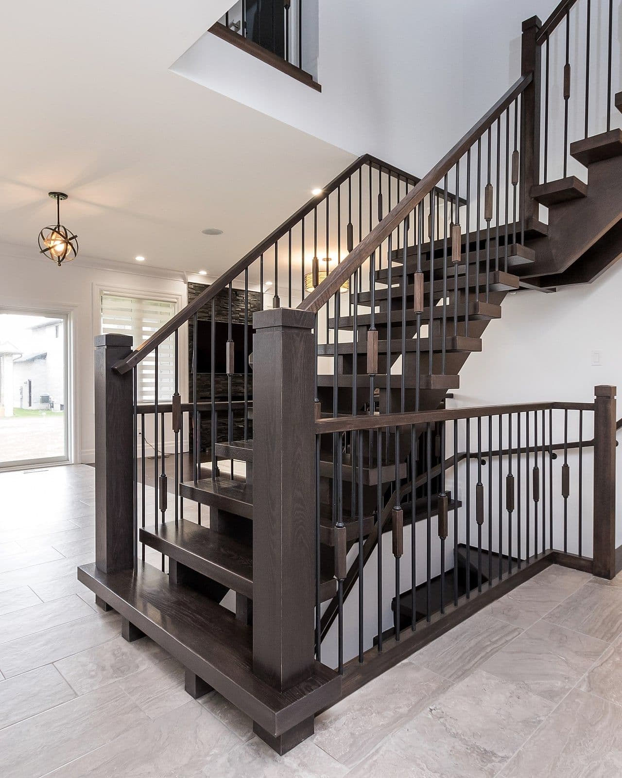 Stained-oak staircase with iron spindles in a Foxwood Crossings home