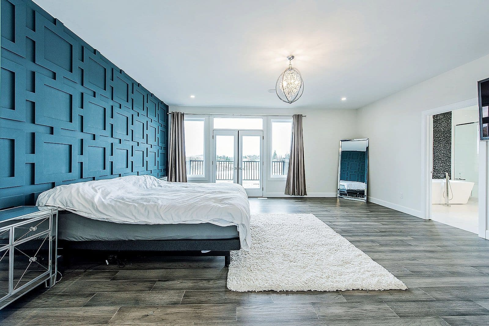Primary bedroom with a blue feature wall and large windows