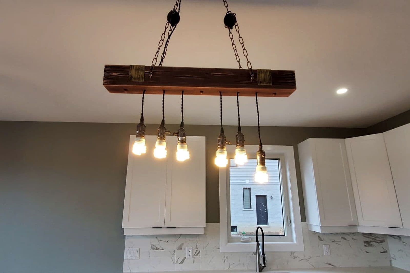 Kitchen island beneath a reclaimed-timber light fixture
